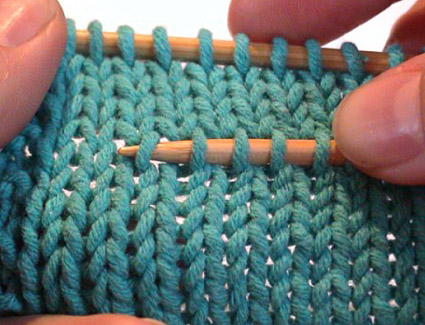 Notice she picks up the RIGHT LEG of each stitch so that they will be sitting properly on the new needle when the above rows are removed.
